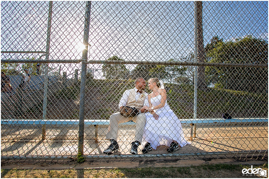 Bride and groom kissing in baseball dugout. 